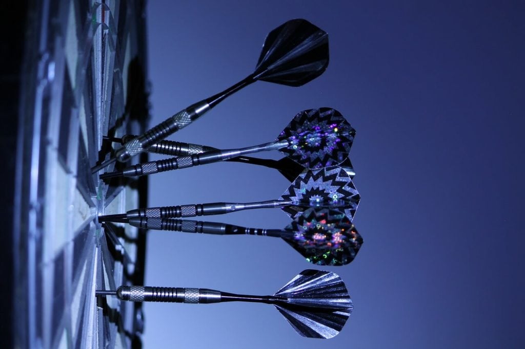 A photograph of five darts attached to a dartboard.